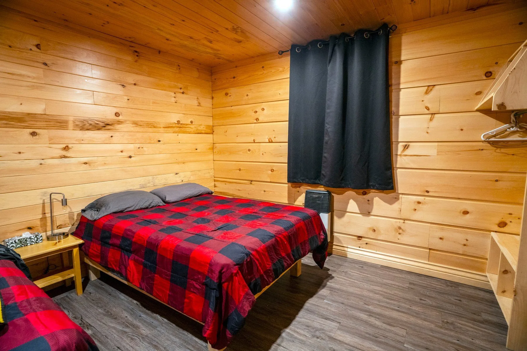 Dormitorio de chalet de madera con edredón a cuadros rojo y negro